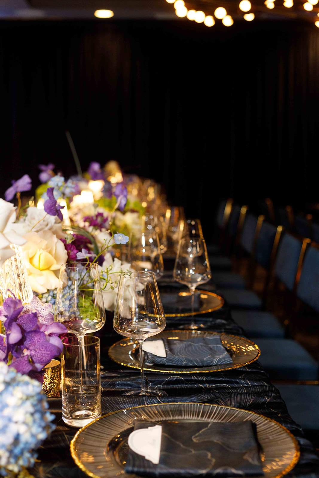 A long candlelit dinner table with jewel-toned florals at Rhasheda's 50th