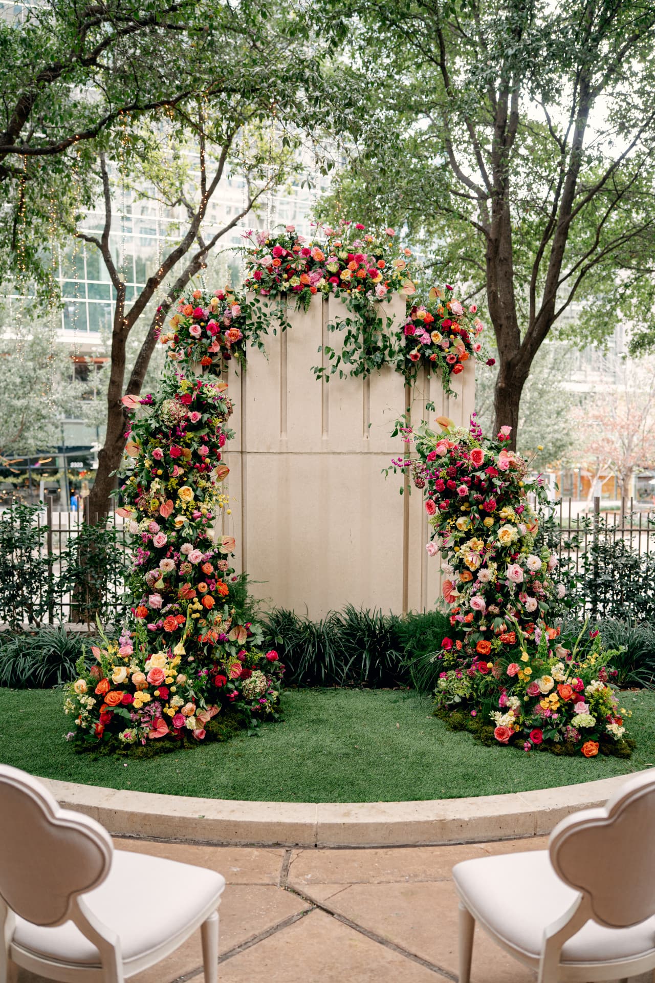 An outdoor ceremony arch at Avani and Kevin's wedding, overflowing with roses and trailing greenery